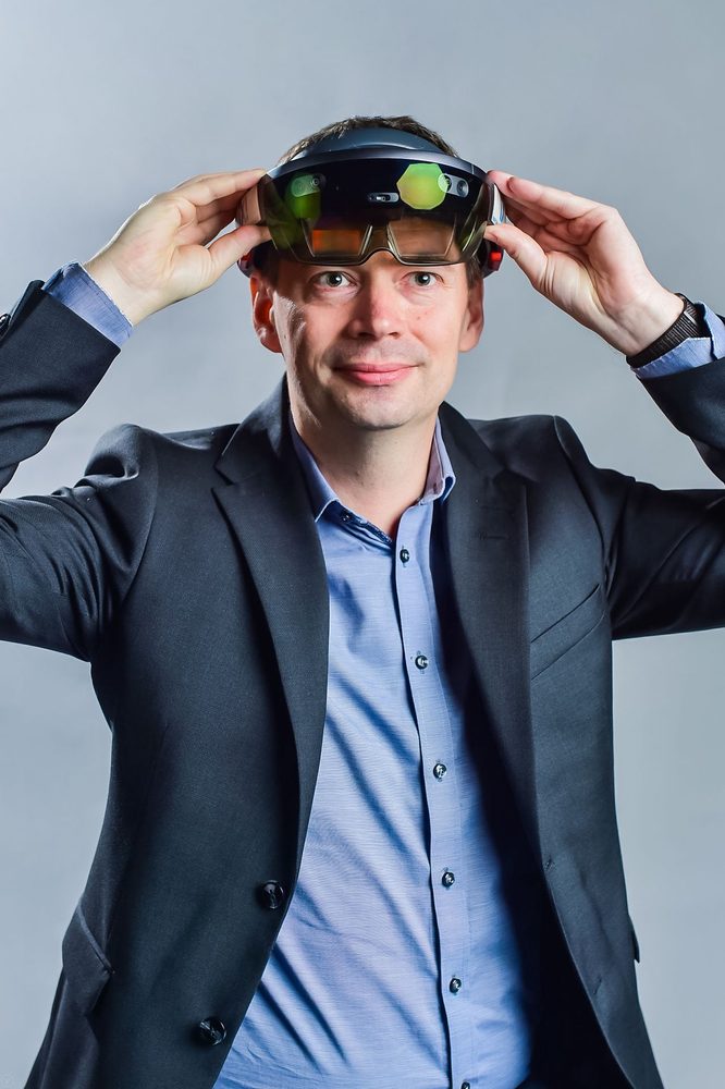 Anders Lundgren i kavaj lyfter visiret på ett par HoloLens upp mot pannan.